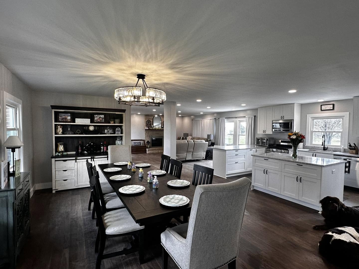 Moegling remodeled open kitchen and dining room with white cabinetry and dark wood flooring
