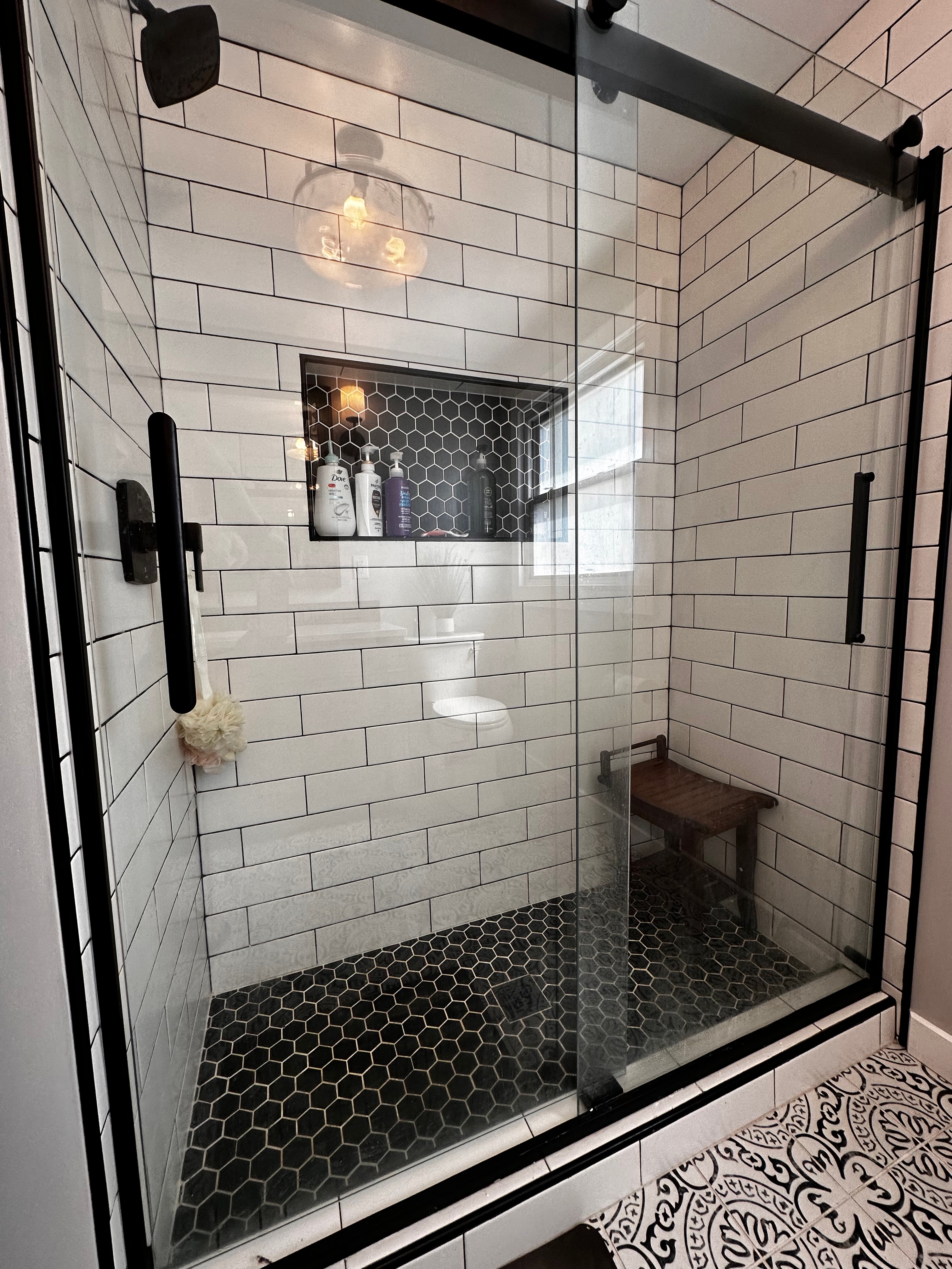 Subway tile shower with dark mosaic detail