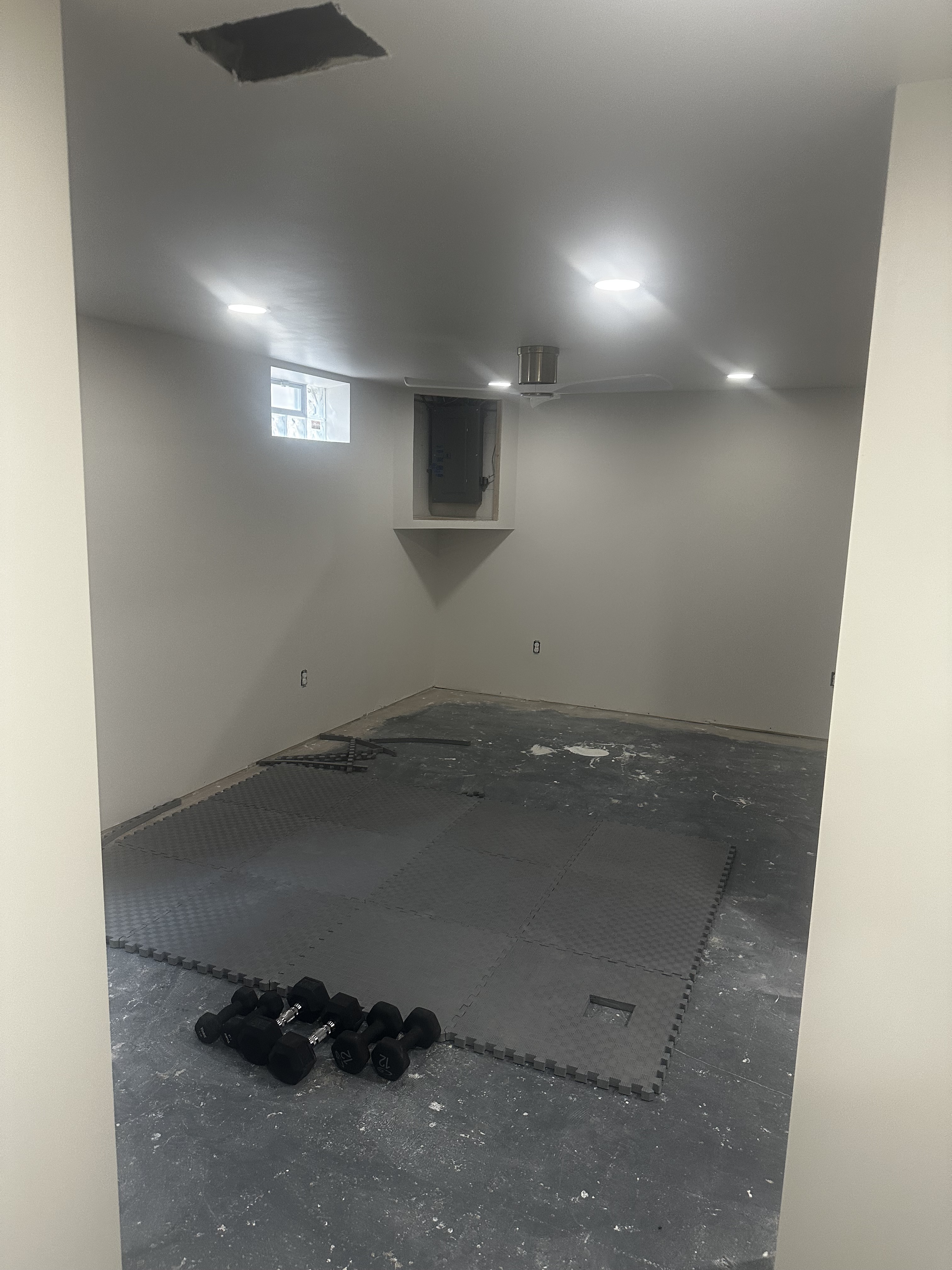 The same basement bedroom before finishing, with workout mats and unfinished floor