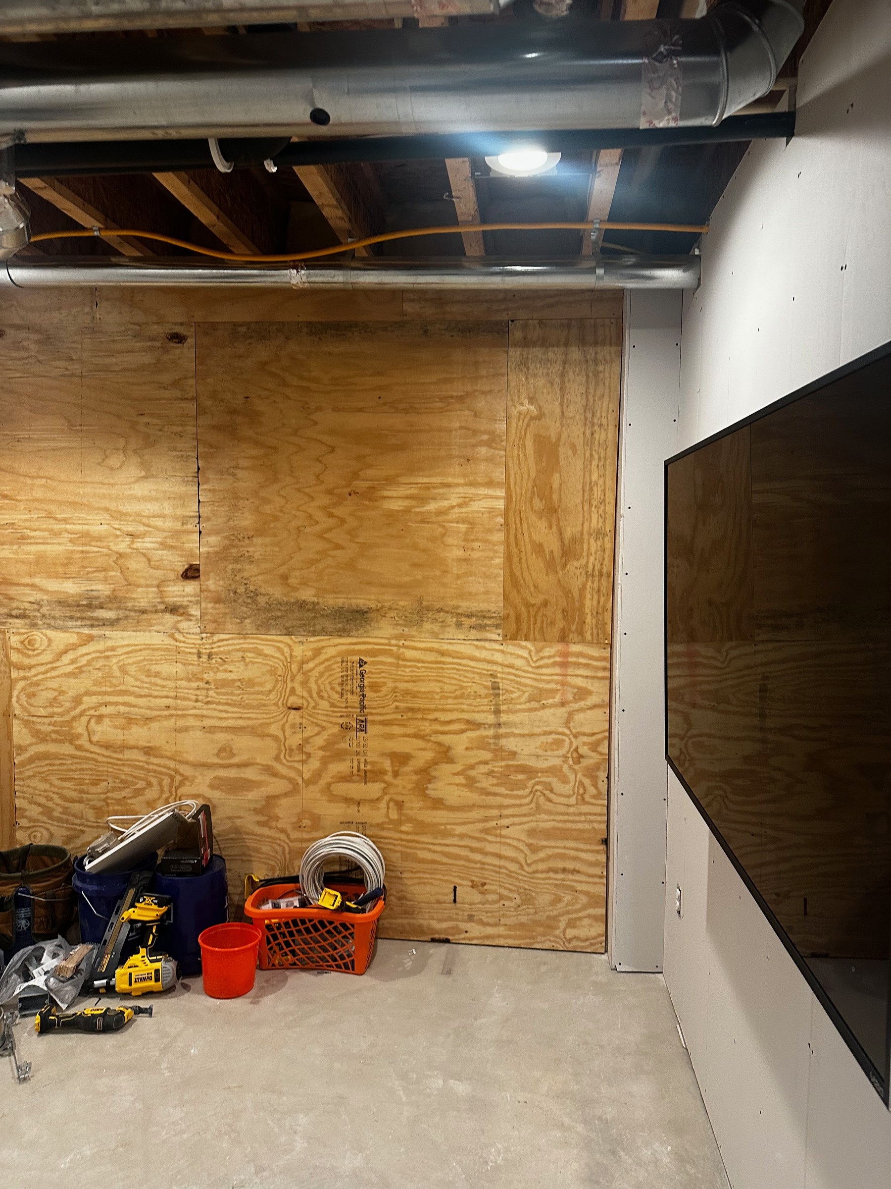 The same Dublin basement gym during finishing, with exposed ductwork and a plywood-covered wall